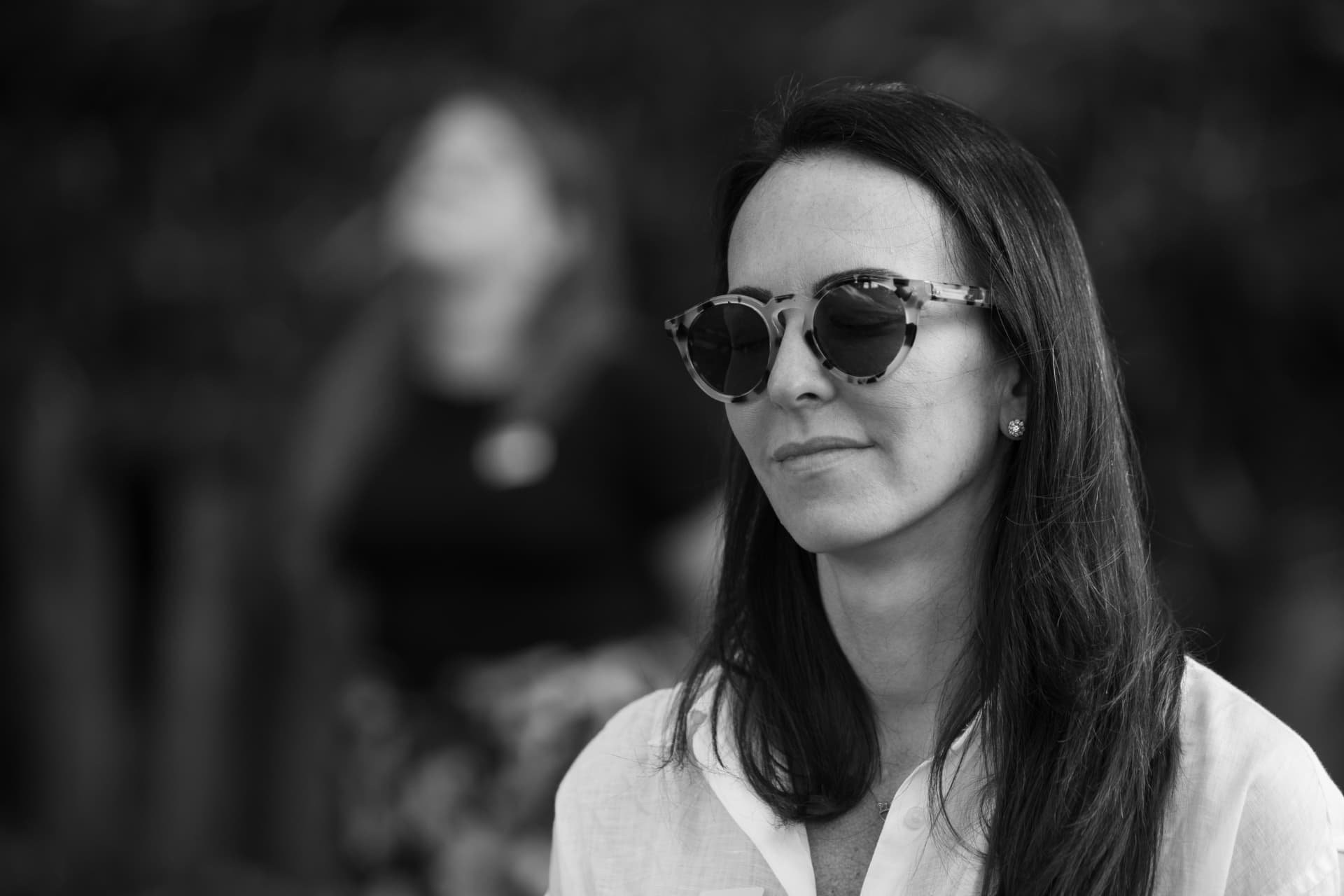 A woman wearing round patterned sunglasses, in black and white